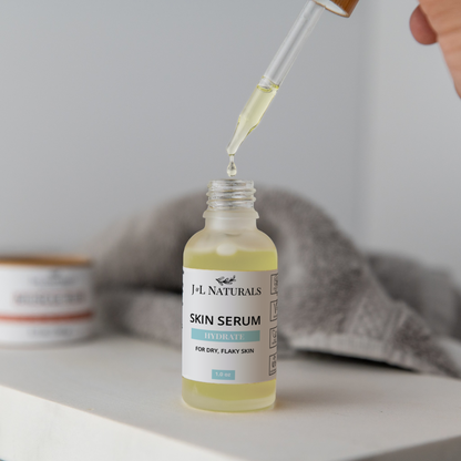 Skin Serum Duo bottle with dropper dispensing hydrating serum for dry, flaky skin on white surface with blurred towel background