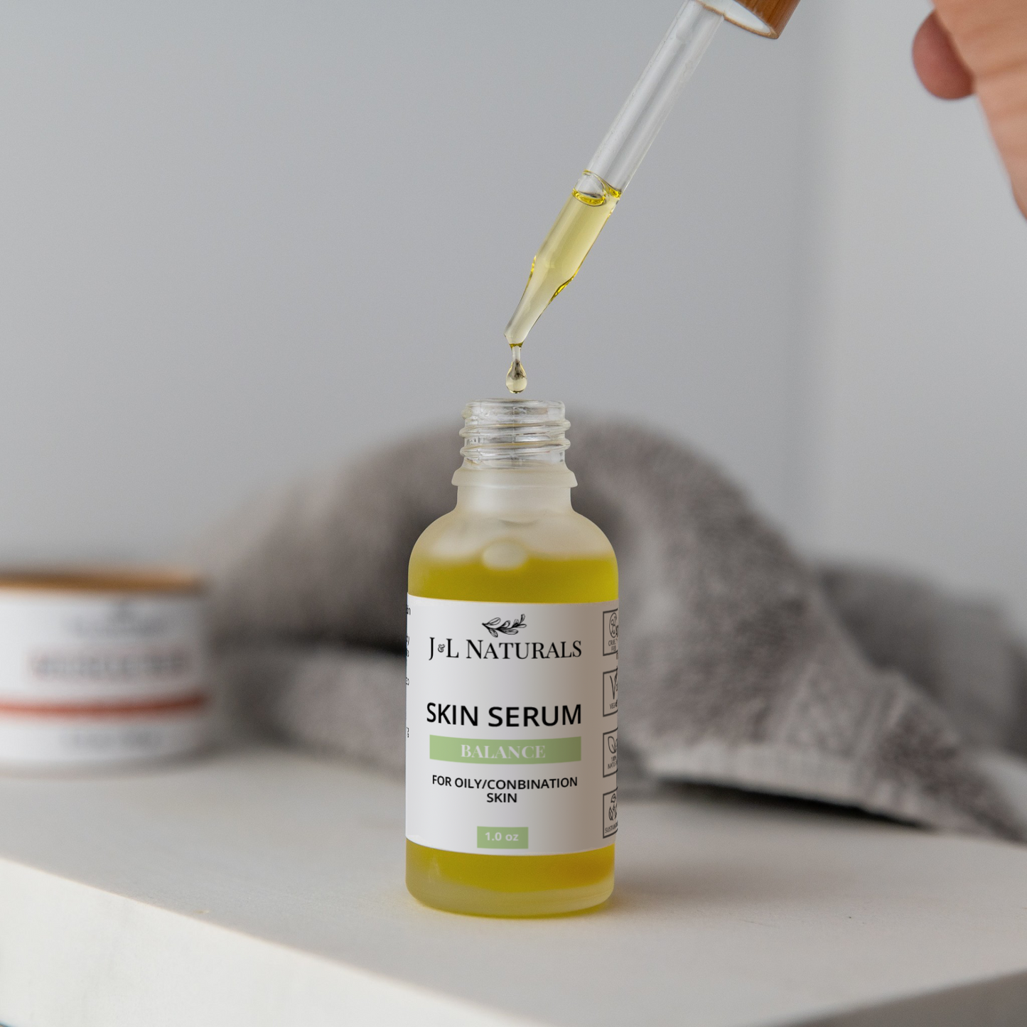 Skin Serum Duo dropper dispensing plant-powered hydrating serum in glass bottle for oily combination skin on white surface with towel background